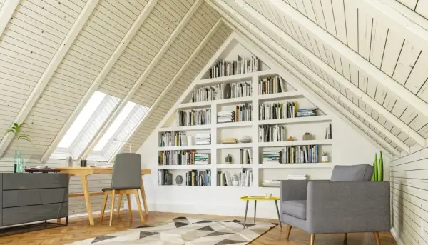 Gemütlicher Arbeitsplatz mit Bücherregalen im Dachausbau. Ein Schreibtisch unter Dachfenstern und eine Leseecke laden zum Verweilen ein.