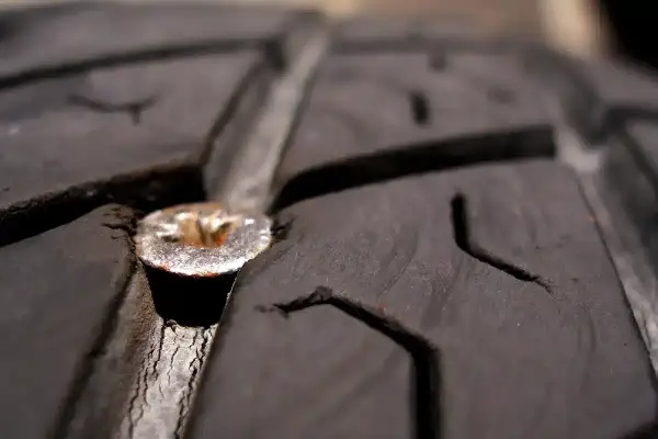 Une mèche est plantée dans le pneu d'une voiture, causant une crevaison.