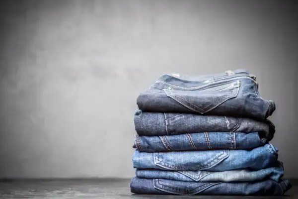 Stosik złożonych jeansów, każdy w innym odcieniu niebieskiego. Z czego jest jeans? Z bawełny, tkanej diagonalnie, co nadaje mu wytrzymałość.