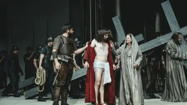 Szene aus einem Passionsspiel: Jesus mit Dornenkrone, umgeben von Soldaten und Frauen, die ein Kreuz tragen.