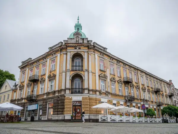 Kamienica w Radomiu z żółtą fasadą, kopułą i kawiarnią na parterze.