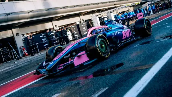 Coche de **Alpine F1** azul y rosa listo para la carrera en el pit lane.