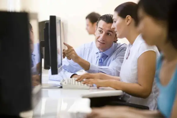 Uomo indica schermo a collega, mentre lei digita. Un tirocinio extracurriculare con stipendio è un'ottima opportunità.