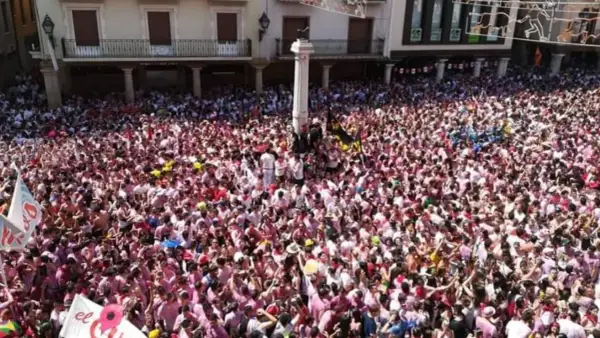Multitudinaria plaza en las fiestas del Torico de Teruel, con gente vestida de blanco y rosa celebrando.