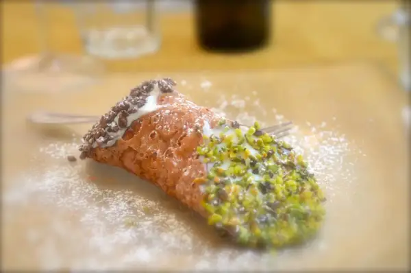 En krispig cannelloni dessert med pistagenötter och chokladströssel, pudrad med florsocker.