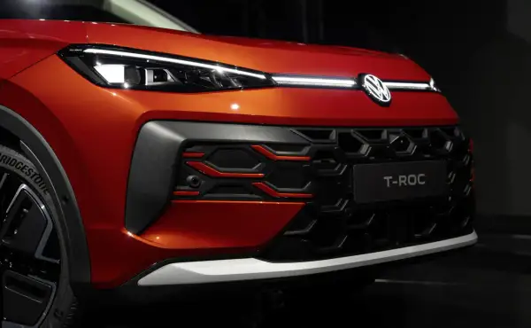 Pomarańczowy Volkswagen T-Roc z nowoczesnymi światłami IQ.LIGHT i charakterystycznym grillem.