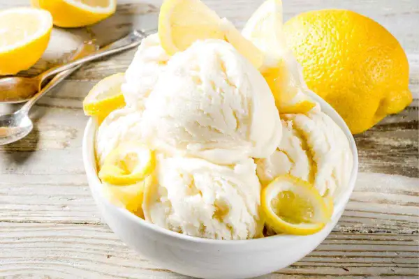 Coppa di cremoso gelato al limone bimby, guarnita con spicchi freschi. Un'esplosione di freschezza estiva.