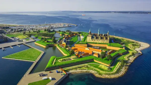 Kronborgs slott vid sundet, en del av Danmarks natur, med en stor marina och grönskande vallgravar.