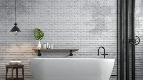 Bagno moderno con vasca bianca, mattoni a vista e tubi industriali neri. Ottime idee per coprire tubi a vista con stile.