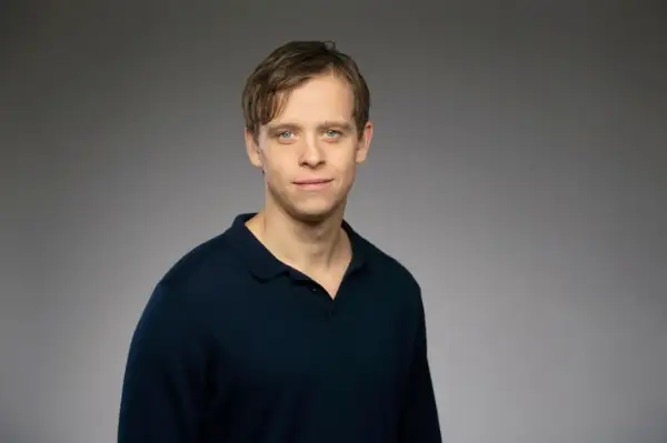 David Pålsson, en ung man med blå ögon och brunt hår, bär en mörkblå pikétröja.