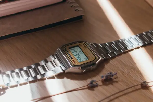 Reloj Casio plateado sobre madera. Aprende como saber si un reloj es original observando sus detalles.