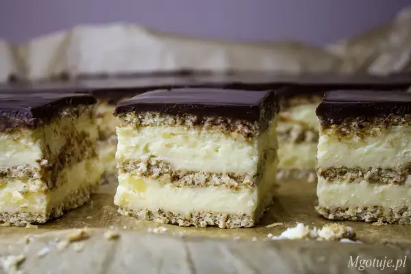 Kawałki pysznego, gotowanego sernika z czekoladową polewą, ułożone na papierze do pieczenia.