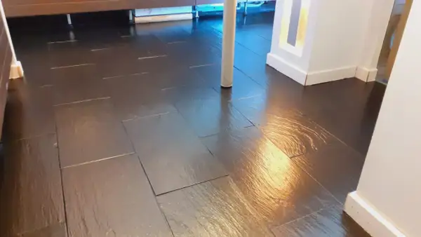 Pavimento in bollettonato di marmo scuro, lucido e riflettente, con un pilastro bianco al centro.