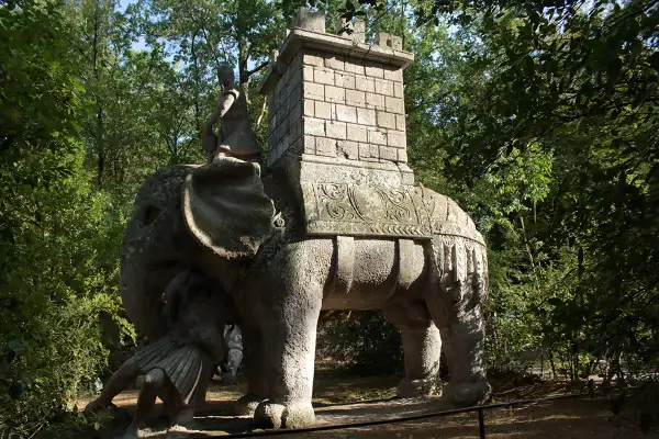 Elefante di pietra con guerriero e torre nel viterbo giardino dei mostri. Un'antica creatura che emerge dal verde.