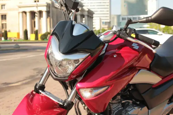 Błyszczący, czerwony motocykl Suzuki Inazuma z czarnym akcentem na przedniej owiewce, gotowy do jazdy po mieście.