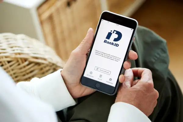 Person håller upp en telefon med BankID-appen öppen, redo för inloggning eller underskrift. Perfekt för din bankID ny telefon.