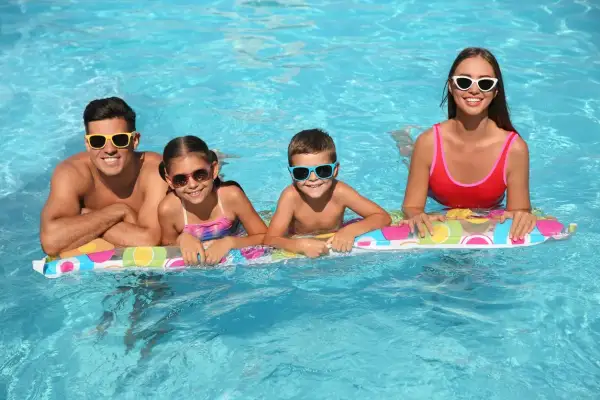 Famiglia felice in piscina, in attesa dello stipendio 15 agosto. Sorrisi e occhiali da sole per tutti!