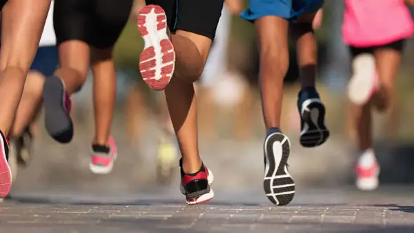 Des coureurs en action, leurs jambes et chaussures en mouvement. Une scène dynamique pour apprendre à courir.