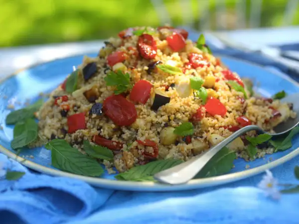 Piatto colorato di cous cous integrale con verdure miste, pomodorini e basilico. Un'idea gustosa per le tue cous cous integrale ricette.
