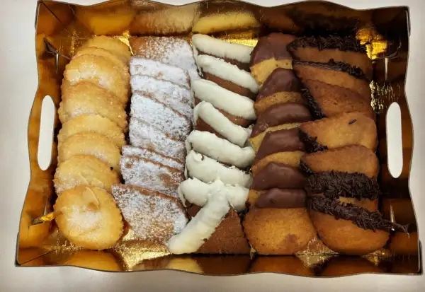 Bandeja dorada con surtido de galletas: almendradas, espolvoreadas con azúcar glas, bañadas en chocolate blanco y negro. ¡La mejor pastelería Zaragoza!