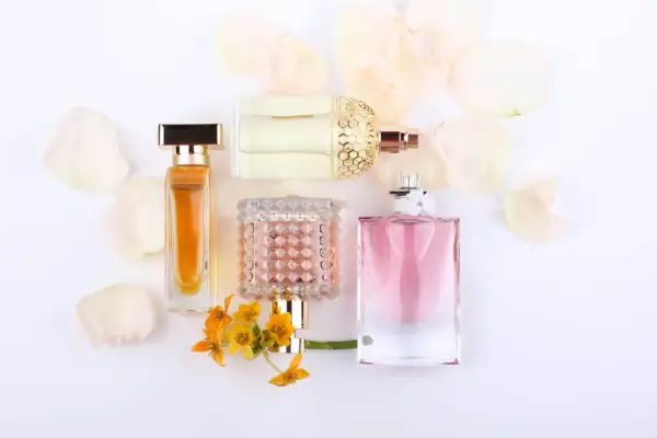Eleganckie flakony perfum, w tym te z nutami feromonów damskich, otoczone płatkami kwiatów.