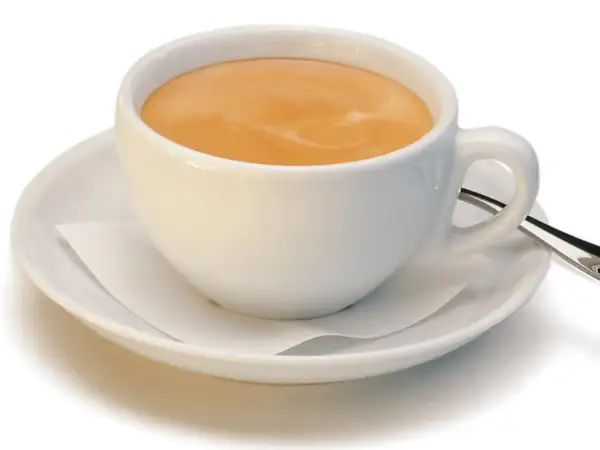 Ein kleiner brauner Kaffee mit Milchschaum in einer weißen Tasse auf einer Untertasse.
