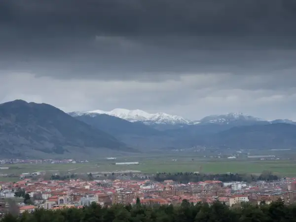 Widok na miasto Korce w Albanii z ośnieżonymi górami w tle.