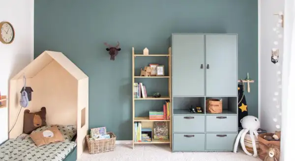 Gemütliches Kinderzimmer für Grundschulkinder mit Hausbett, Bücherregal und Spielzeug.