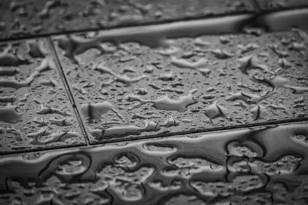 Gouttes d'eau sur un carrelage qui se décolle, signe d'une humidité persistante.
