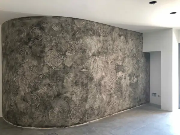Parete curva con un suggestivo intonaco a calce decorato con motivi floreali e geometrici in stile damascato.