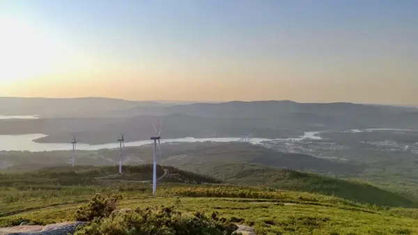 Vistas del monte Xiabre con molinos de viento y un río al atardecer.