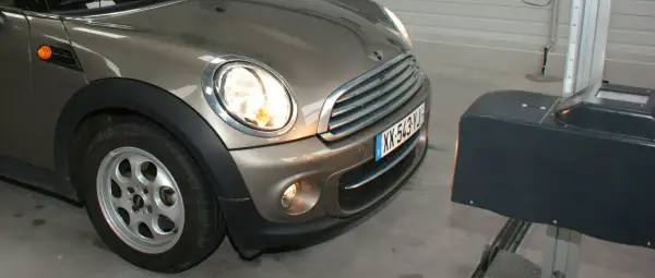 Réglage des feux diurnes d'une Mini Cooper marron, avec un appareil de mesure à droite.
