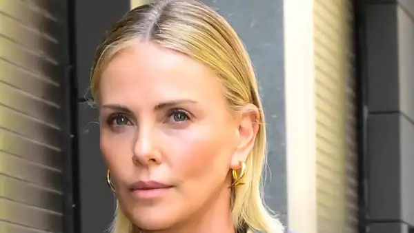Charlize Theron, bez męża, w złotych kolczykach, patrzy wprost.