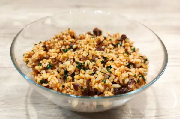 Sałatka z kaszą bulgur i suszonymi pomidorami, pełna smaku i ziół, w szklanej misce.