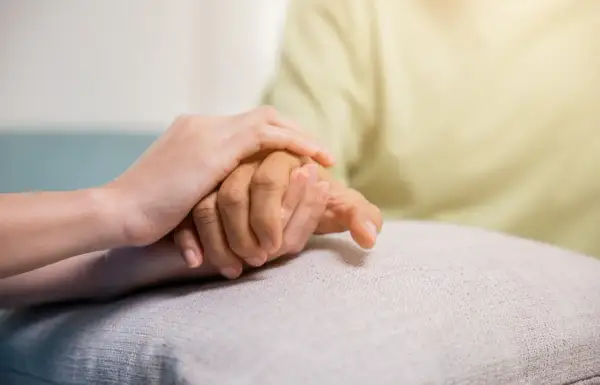 Zwei Hände halten sich fest. Eine jüngere Hand stützt eine ältere, was Hoffnung und Unterstützung für COPD Pflegegrad symbolisiert.