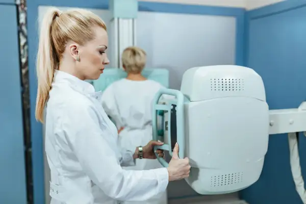 Radiolog przygotowuje aparat do mammografii. Czy mammografia boli? To pytanie zadaje sobie wiele kobiet, ale nowoczesne badania są coraz mniej inwazyjne.