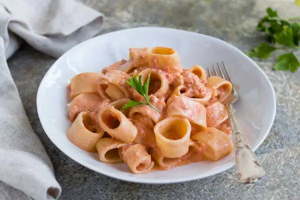 Un piatto di pasta al tonno cremosa, con paccheri conditi e guarniti con prezzemolo fresco.
