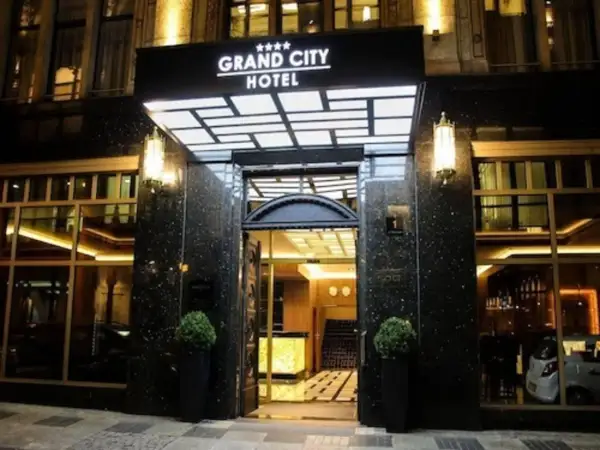 Elegancki **grand city hotel** nocą, z podświetlanym neonem i lśniącym wejściem.