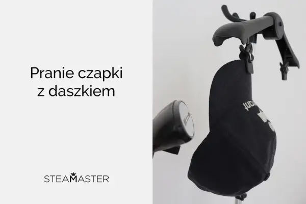 Jak prać czapkę z daszkiem? Czarna czapka zawieszona na wieszaku, obok parownica.