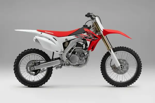 Czerwono-biały motocykl crossowy Honda z widocznym silnikiem i kołami.