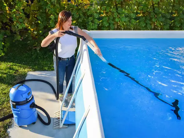 Donna usa un aspiratore per pulire il fondo della piscina, un metodo efficace per capire come pulire la piscina dopo averla svuotata.