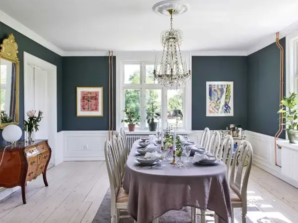 Elegant matsal med dukat bord, kristallkrona och konst. En vacker inspiration för att renovera sekelskifteshus.