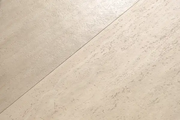Superficie in pietra chiara, con texture irregolare, che appare satinato o opaco.