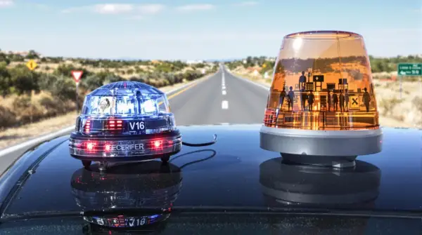 Deux gyrophares sur le toit d'une voiture, sur une route déserte. L'un est bleu et rouge, l'autre orange avec des silhouettes. Indispensable équipement obligatoire voiture Espagne pour la sécurité.