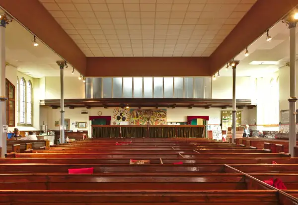 Intérieur d'une église protestante, avec des bancs en bois verni et une fresque colorée au mur. Un lieu paisible pour un baptême chez les protestants.