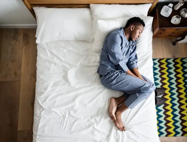 A man sleeps on his side, curled up. What does the way you sleep say about you?