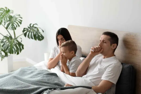 Rodzina w łóżku, kaszląca i kichająca. Czy zapalenie oskrzeli jest zaraźliwe?