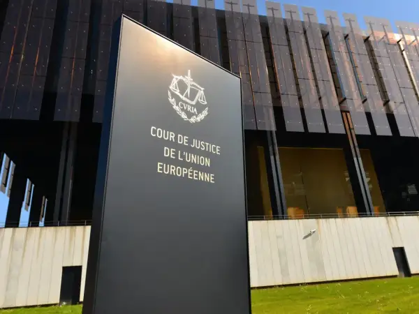 Tablica z napisem "Cour de Justice de l'Union Européenne" przed nowoczesnym budynkiem. To siedziba Trybunału Sprawiedliwości Unii Europejskiej.