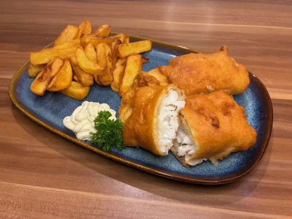 Knuspriges Fish and Chips Rezept: goldbraun frittierter Fisch mit Pommes, dazu Remoulade und Petersilie.