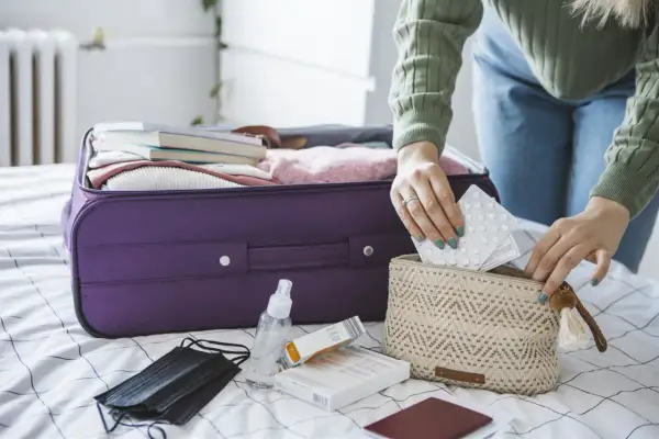 Pakowanie leków do bagażu podręcznego, by wiedzieć jak przewozić leki w samolocie Ryanair. W kosmetyczce tabletki, obok maseczka i płyn do dezynfekcji.